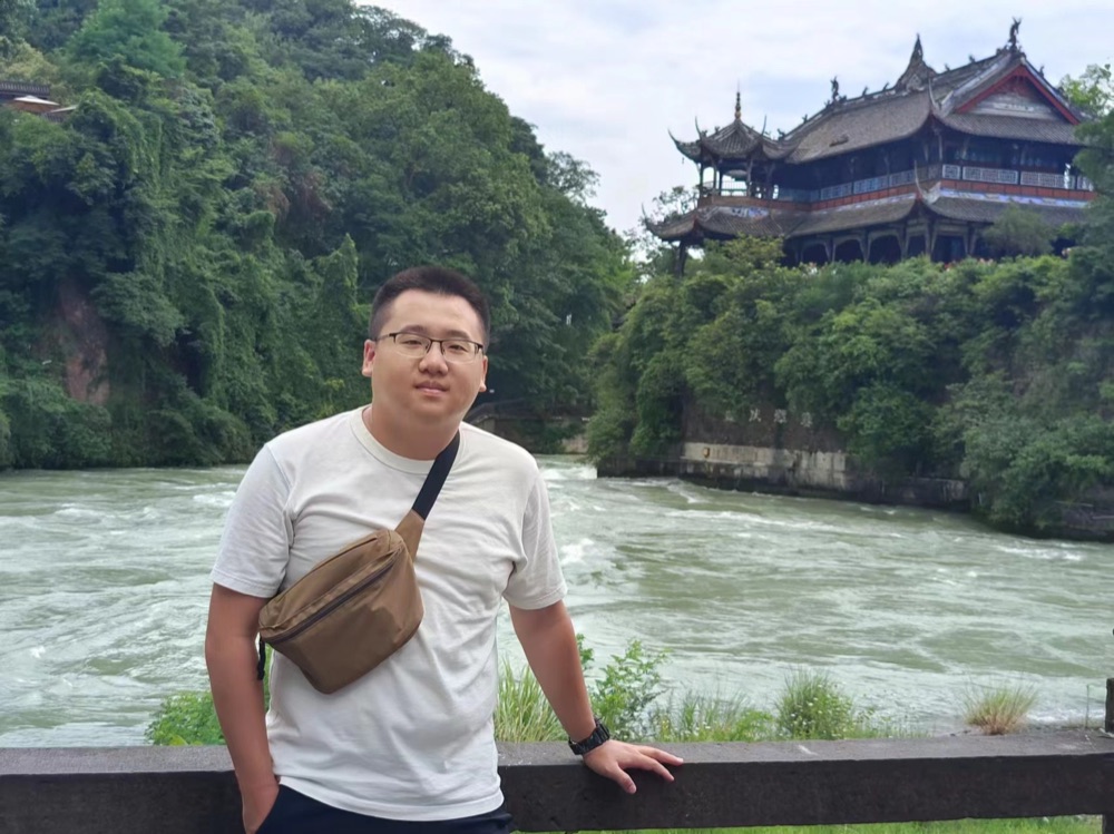 Liang-Ching Tao standing beside a river.